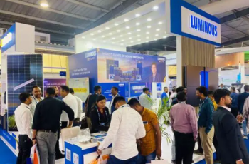 Luminous booth with interactive displays and visitors engaged at The Smarter E India exhibition.